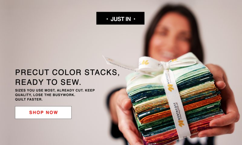 A woman holding a stack of colorfully colored stacks of cloth