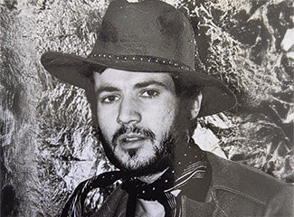 Man wearing a hat and a tie in front of a tree