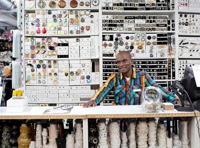 In a colorful shirt sitting at a table with a lot of jewelry