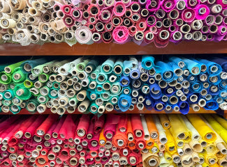 A close up of a shelf of colorful rolls of fabric