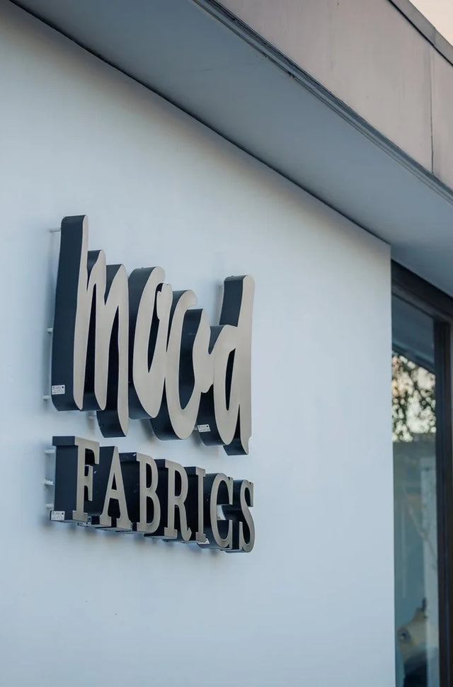 Sign on the side of a building that says mud fabrics
