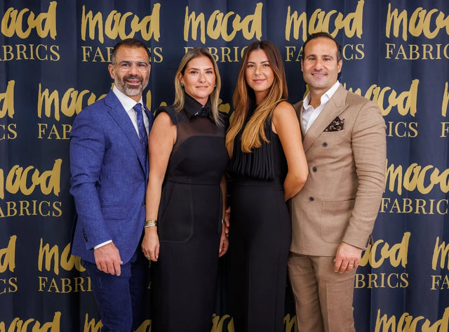 Three people standing in front of a blue backdrop with a gold logo