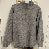 Gray pullover with a quarter zip on a hanger against a white wall.