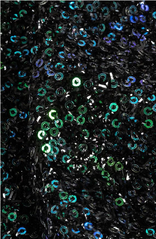 A close up of a black and green sequinized fabric with a lot of green and blue sequins