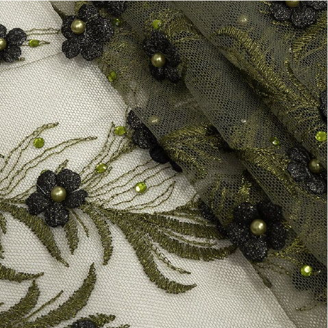 A close up of a green and black floral design on a white fabric