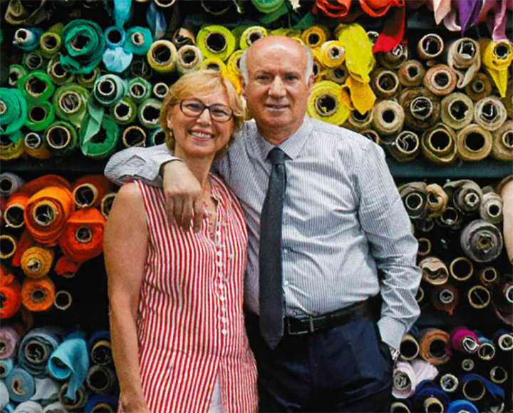 Couple standing in front of a wall of colorful fabrics