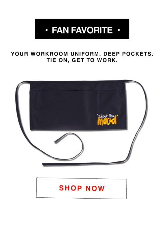 A black apron with a white tag that says fan favorite