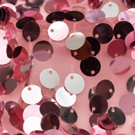 A close up of a pink and black sequinized fabric with lots of different colored sequinized buttons