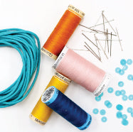 a picture of four spools of thread, a bundle of teal cord, a pile of sewing pins, and loose teal sequins