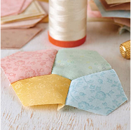 Four pieces of fabric on a table with a spool of thread