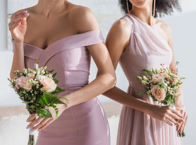 Bridesmaids in pink dresses holding bouquets of flowers in front of a mirror