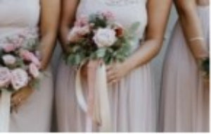 Bridesmaids in pink dresses holding bouquets of flowers in front of a wall