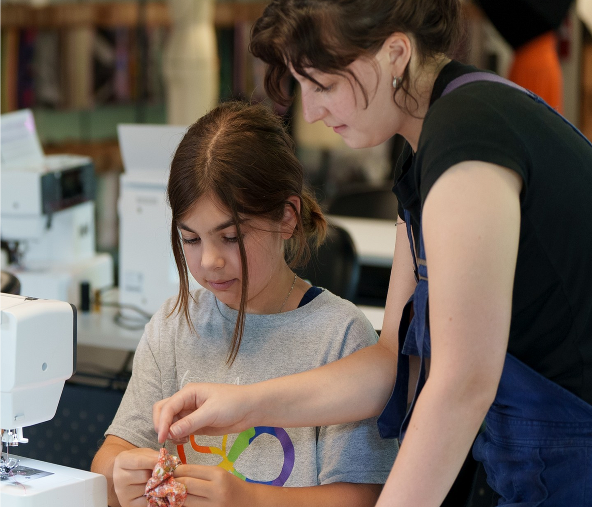 Two girls working on a sewing machine together