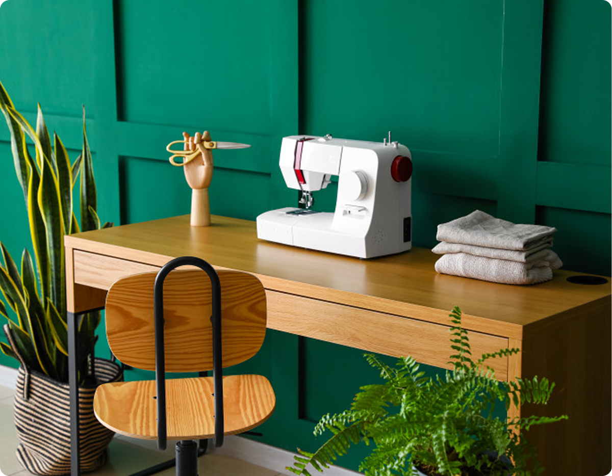 A sewing machine on a wooden table next to a potted plant