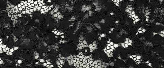 A close up of a black lace fabric with white flowers