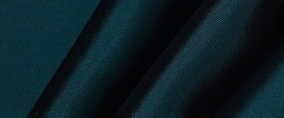 A close up of a dark green fabric with a black background