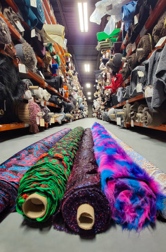 A close up of a store aisle with a variety of different colored fabrics